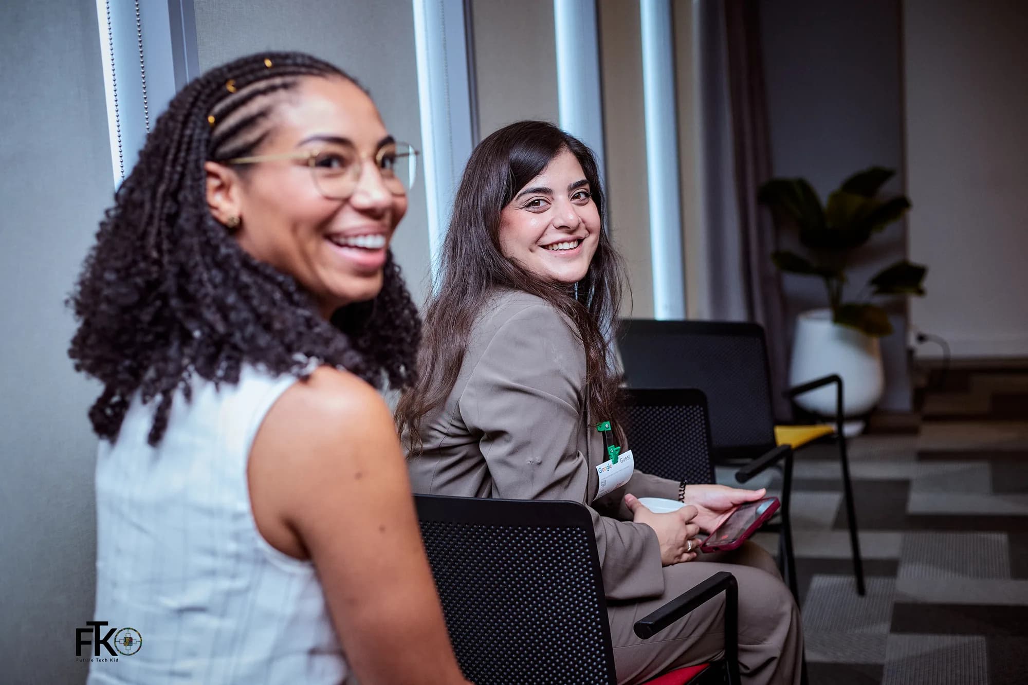 Two attendees turning to smile at the camera during a session