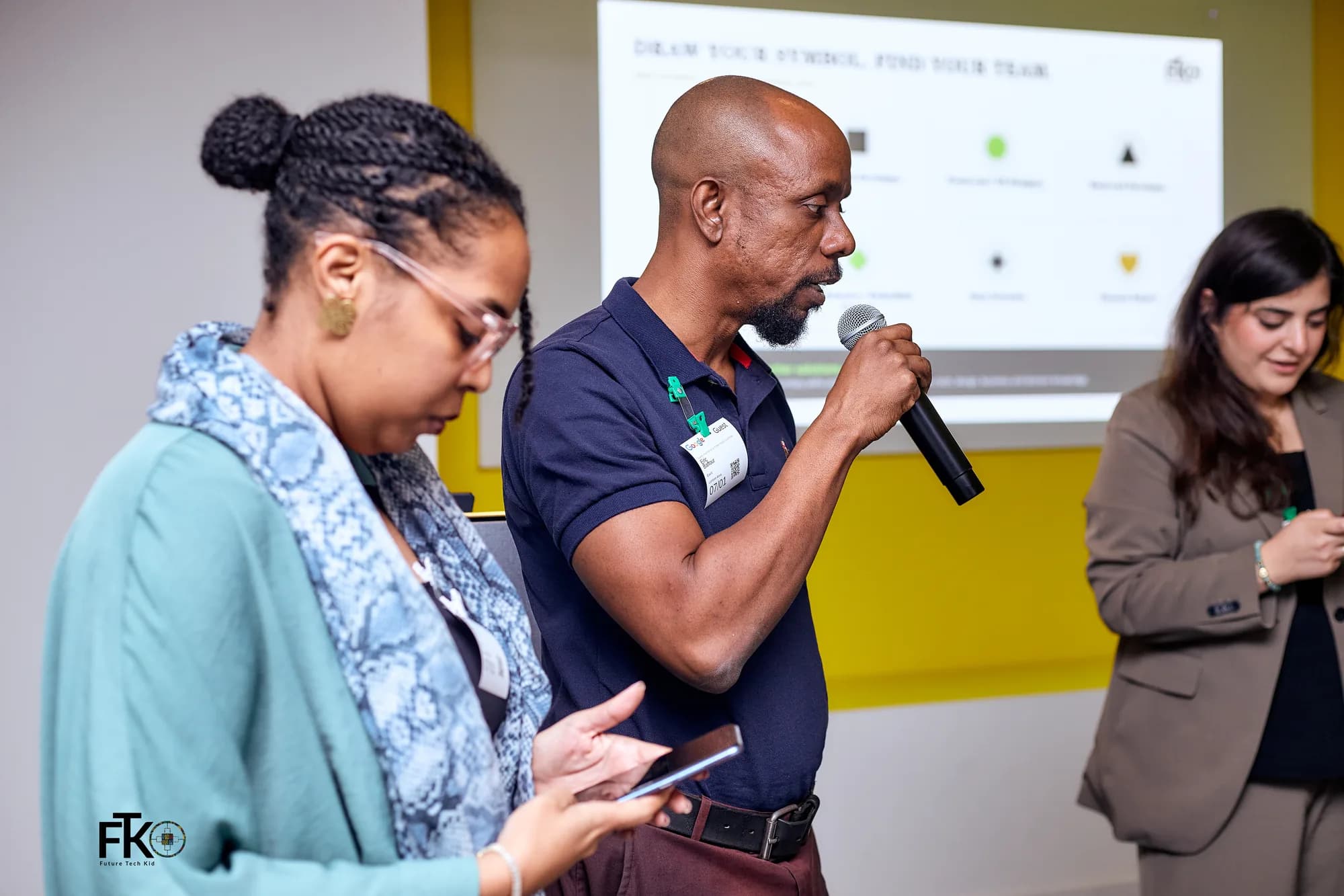 A presenter with a microphone walking a room through a team exercise in Accra